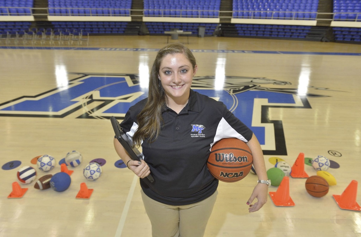 An MTSU physical education student in a gym with sporting equipment.